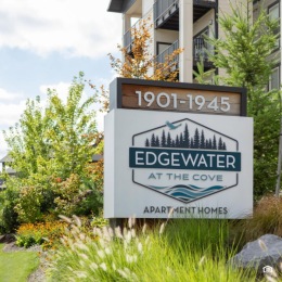 a sign in a flower bed in front of a building