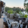 a deck with chairs and tables on it by a body of water