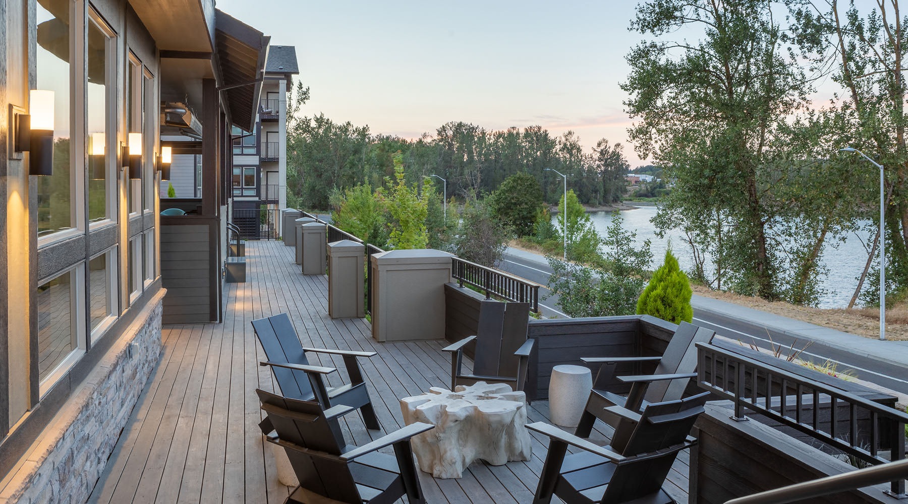 a deck with chairs and tables on it by a body of water