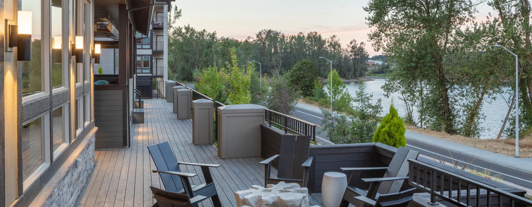 a deck with chairs and tables on it by a body of water